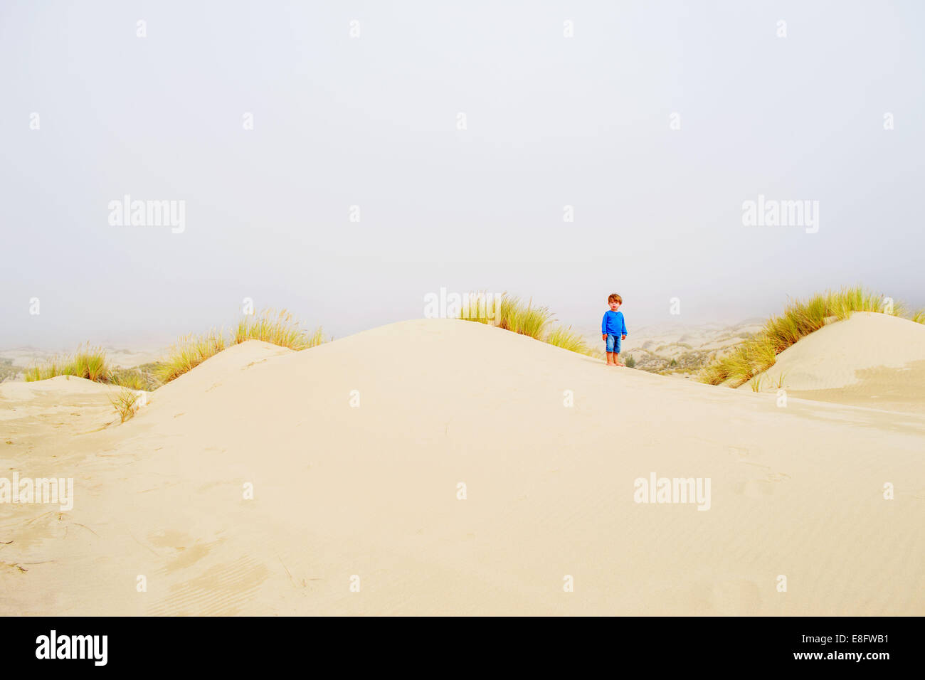 Boy standing amongst sand dunes, USA Stock Photo
