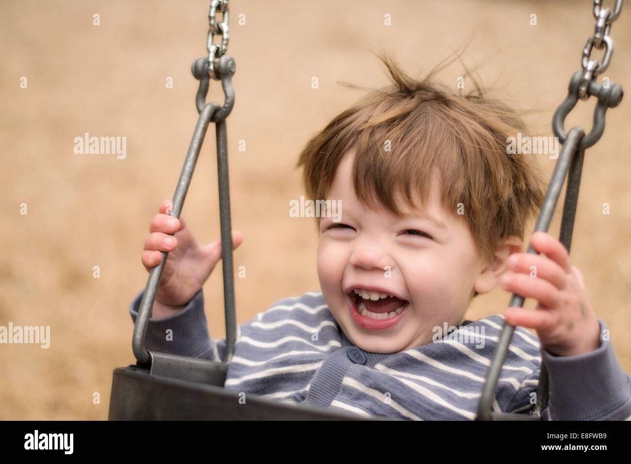 Portrait of a boy on a swing laughing Stock Photo