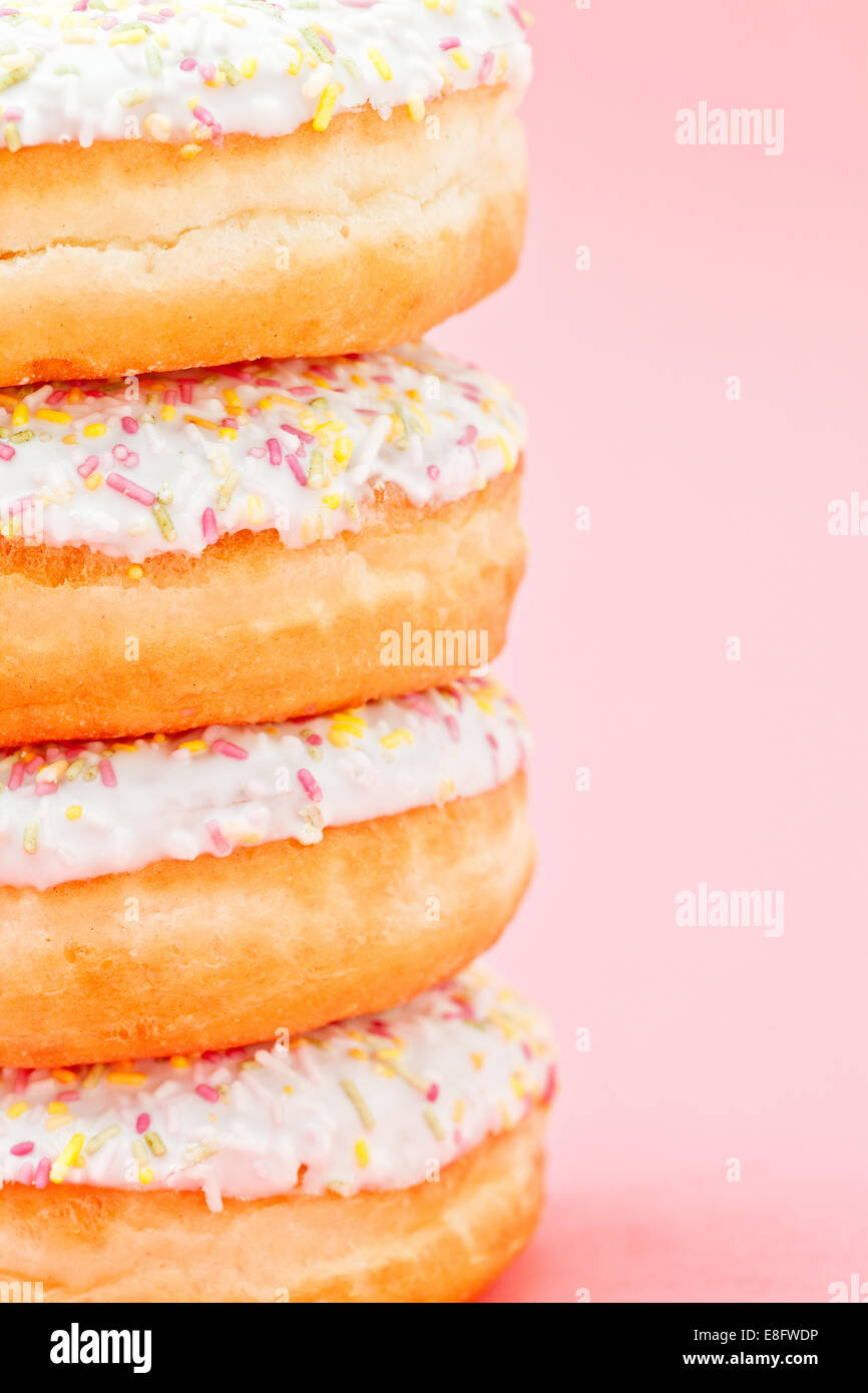 Stack of four iced doughnuts with sprinkles on a pink background Stock ...