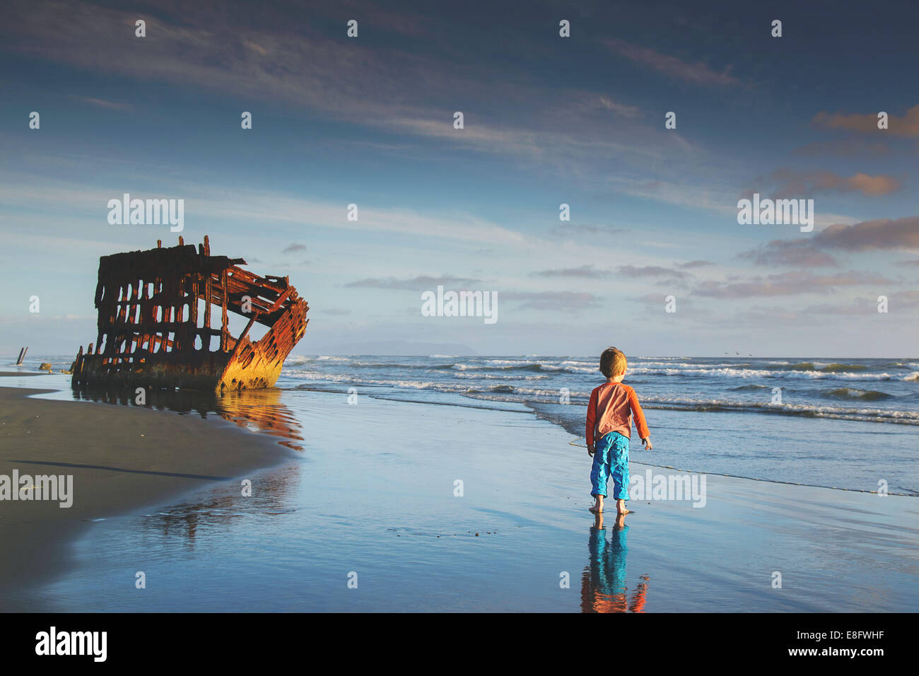 Boy (4-5) walking towards shipwreck Stock Photo - Alamy