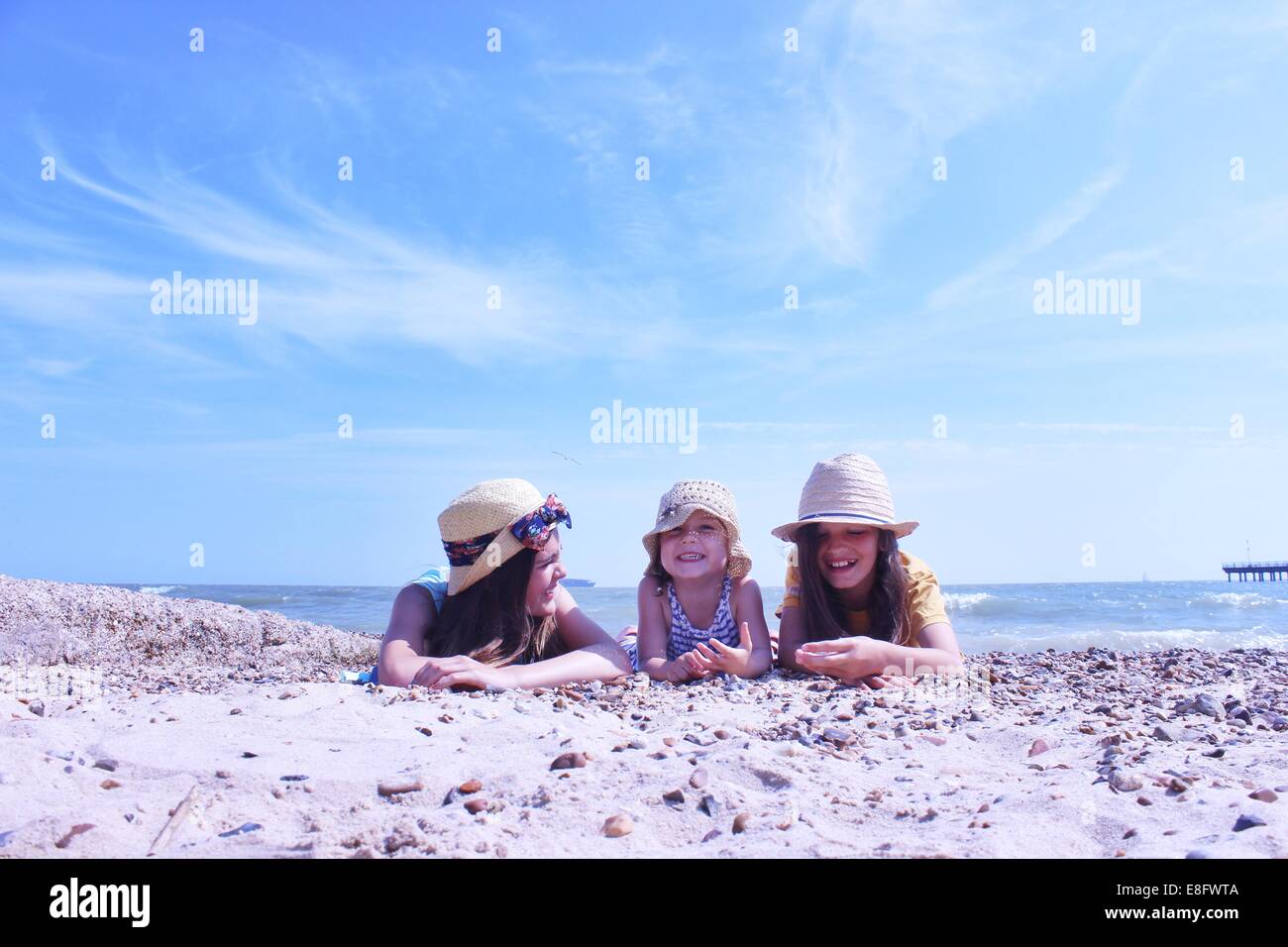 Three Girls on beach lying on their front Stock Photo