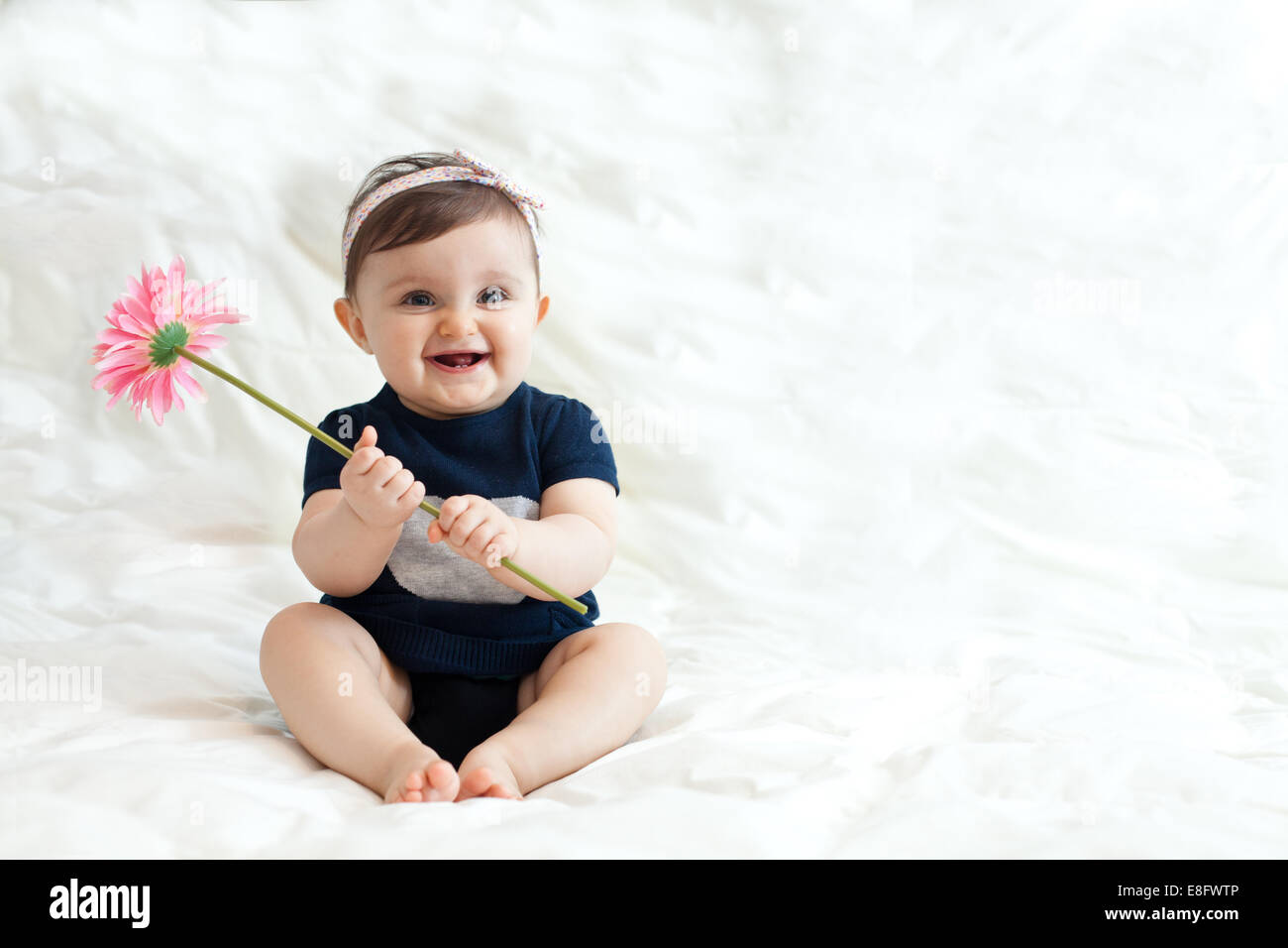 Smiling baby girl holding a plastic flower Stock Photo