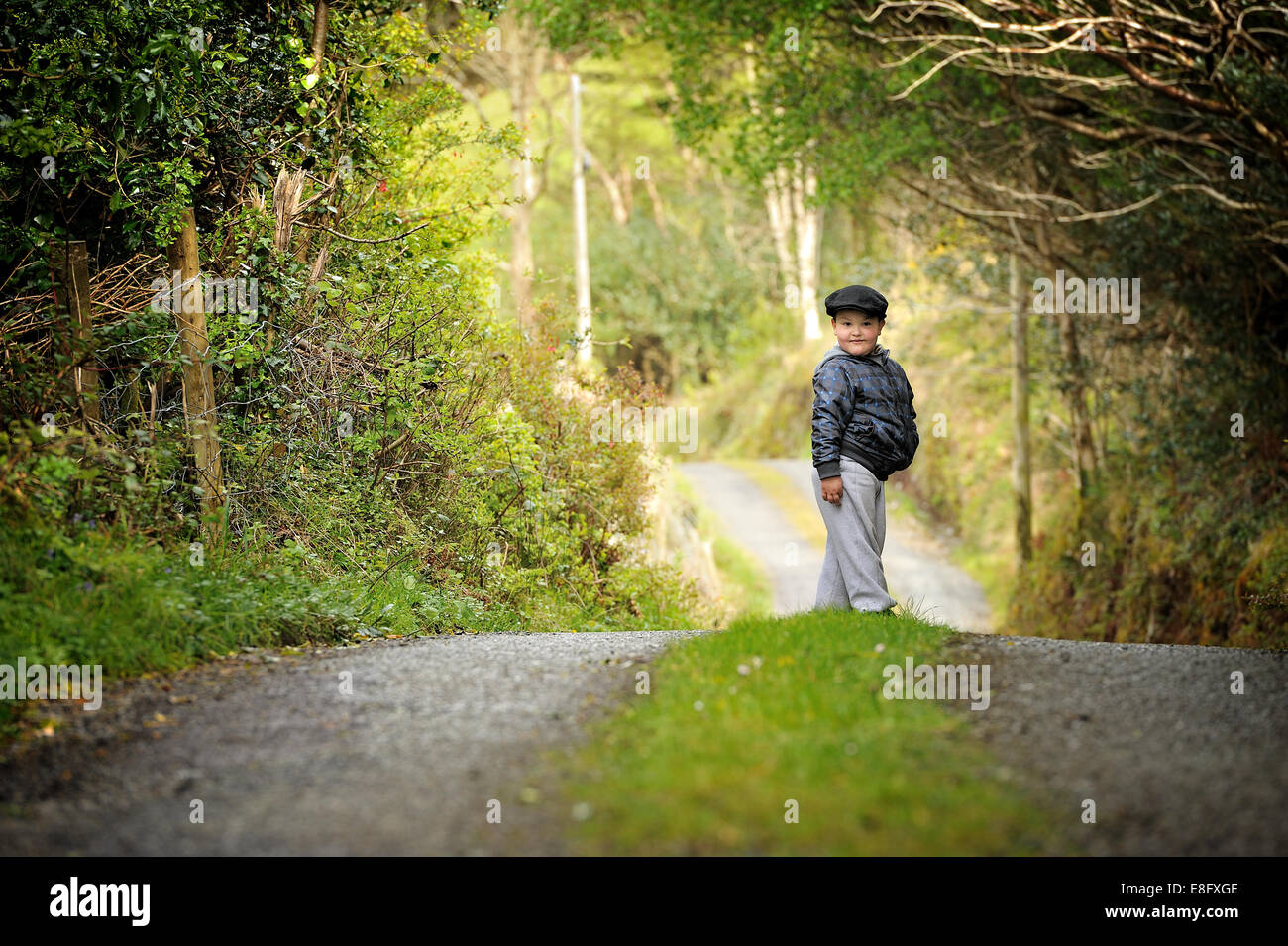 Boy standing in the middle of country road Stock Photo