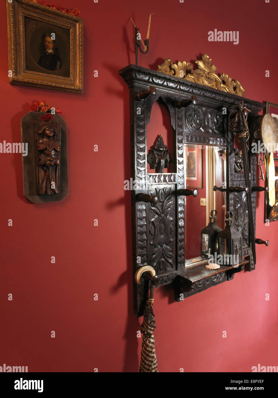 Ornate Victorian mirror and small wooden carving on red wall Stock Photo