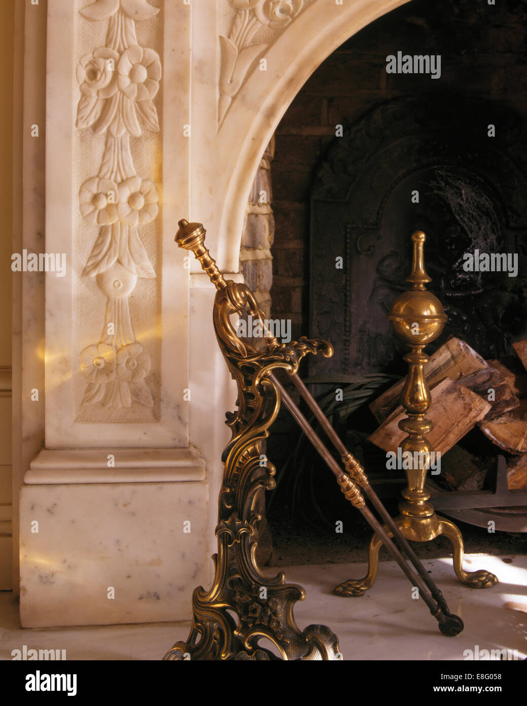 Close Up Of Brass Fire Tongs And Fire Dogs In Marble Fireplace
