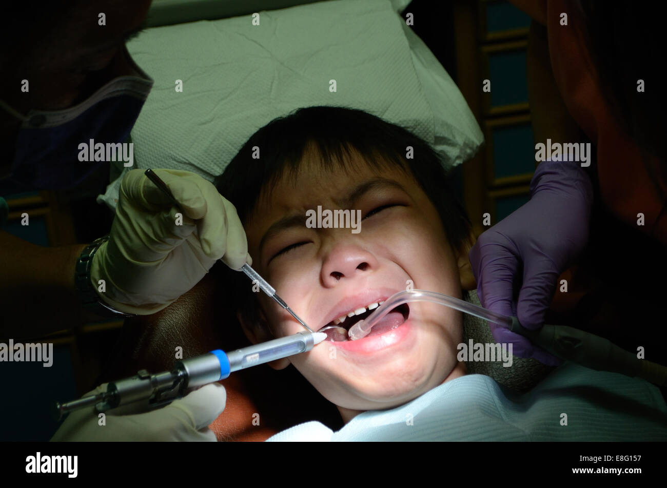 Dentist holding syringe for injection of Asian child, close up Stock