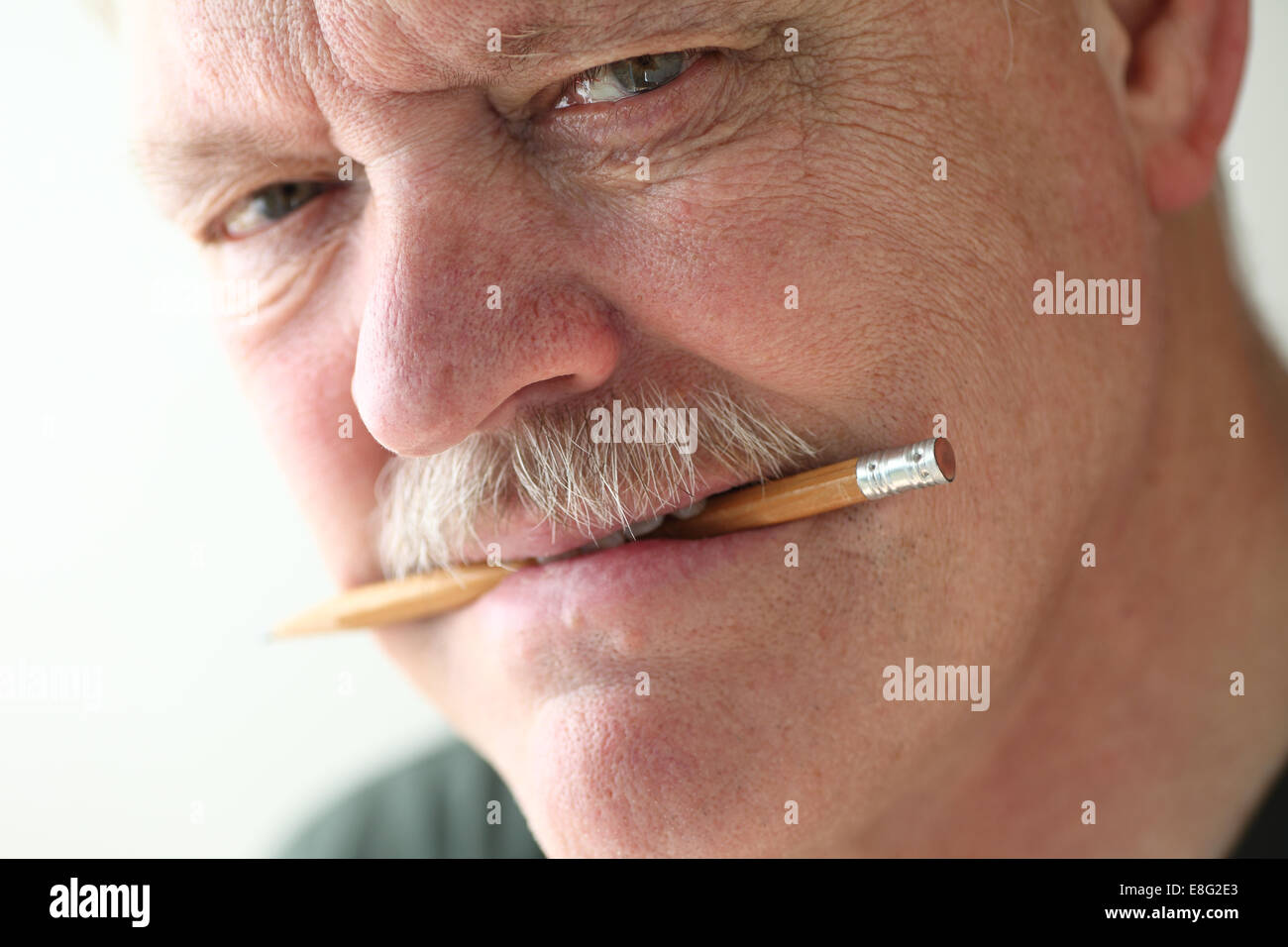closeup of a senior man with a pencil in his mouth Stock Photo
