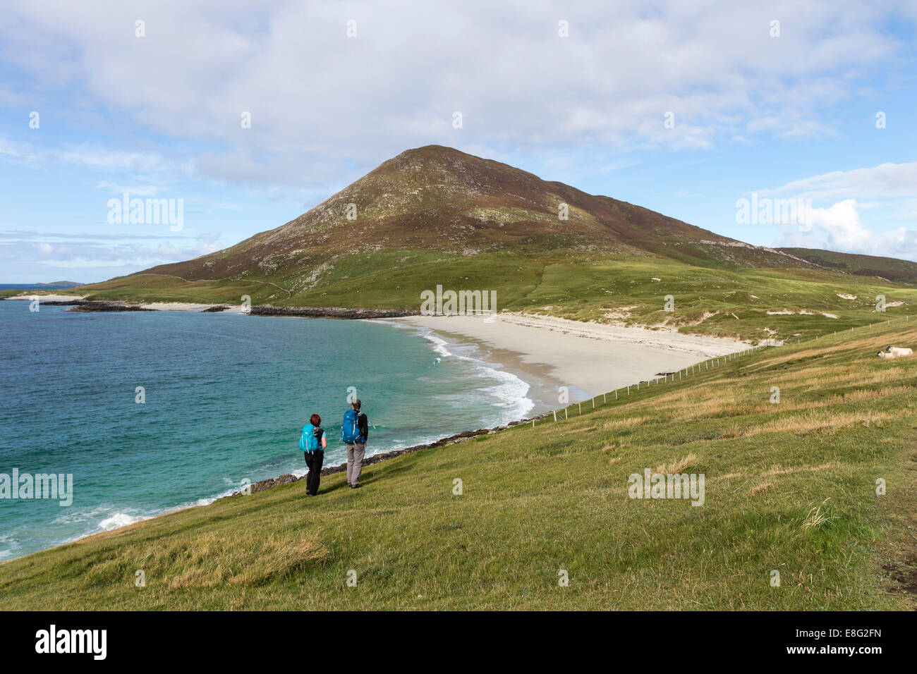 Two Walkers Enjoying the View Over the Beach of Traigh na Cleabhaig to the Hill of Ceapabhal, Isle of Harris Hebrides Scotland Stock Photo