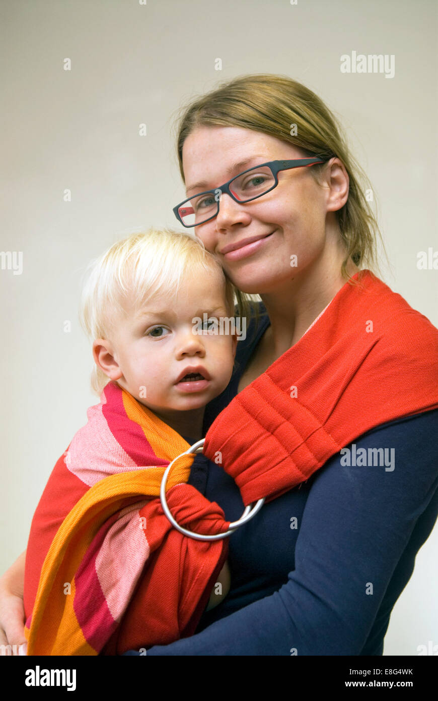 Young mother carrying her 2 year old son in a baby sling, Farnham, Surrey, UK. Stock Photo