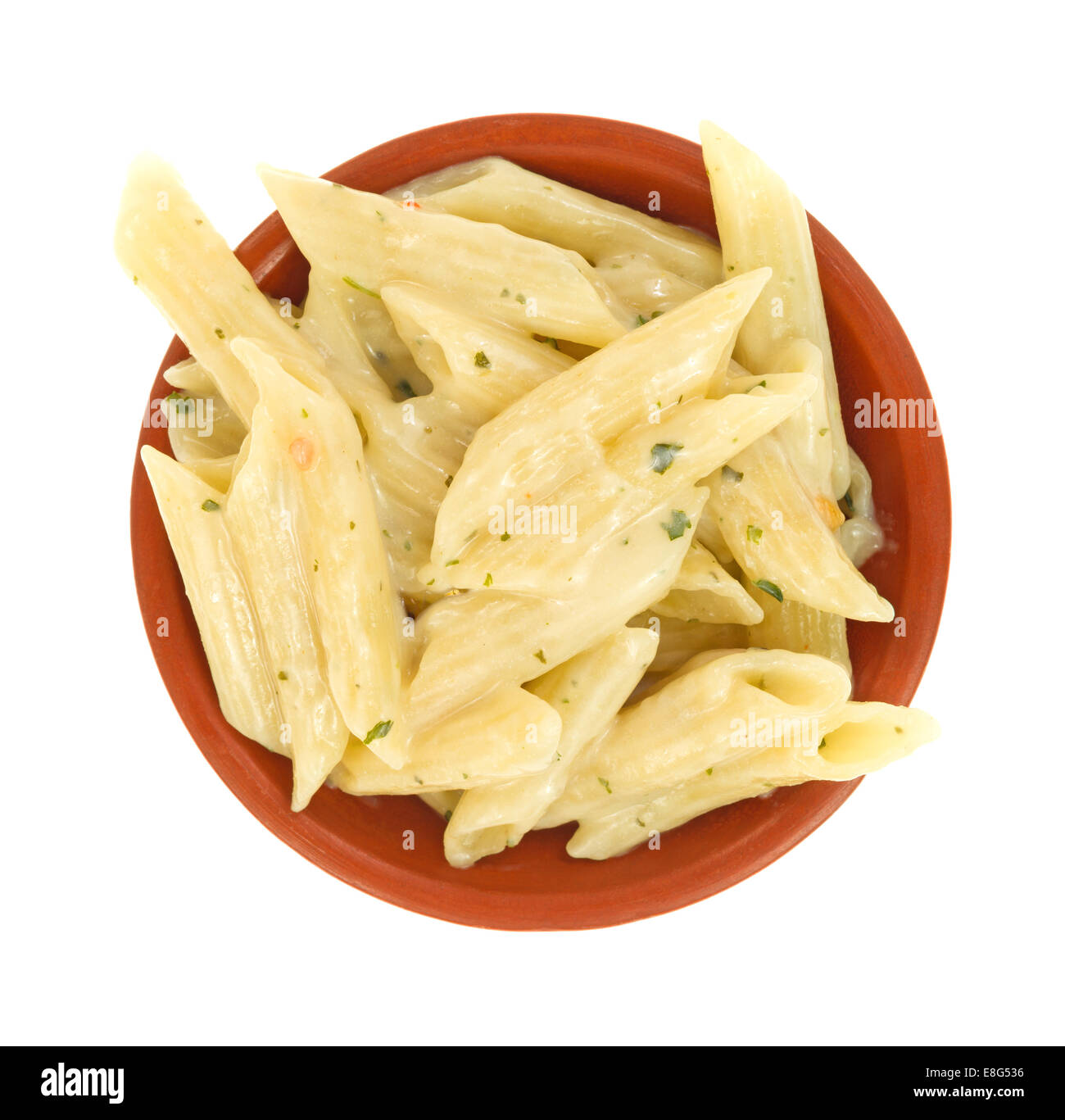 Top view of a small dish of cooked pasta with parsley and garlic in a thick cream sauce on a white background. Stock Photo