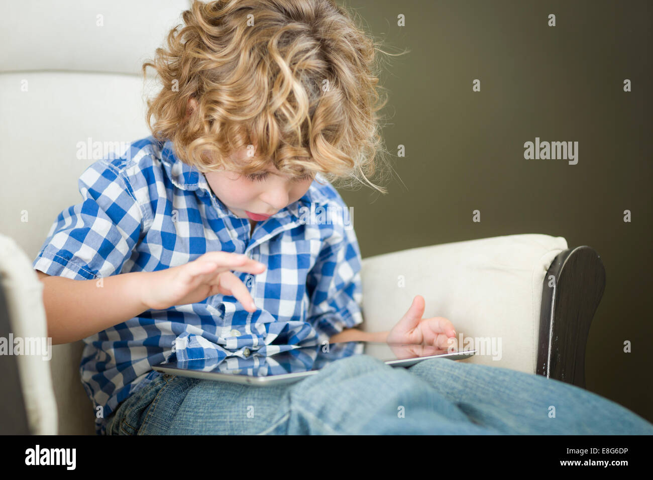 Cute Young Blond Boy Using His Computer Tablet in a Chair Stock Photo ...