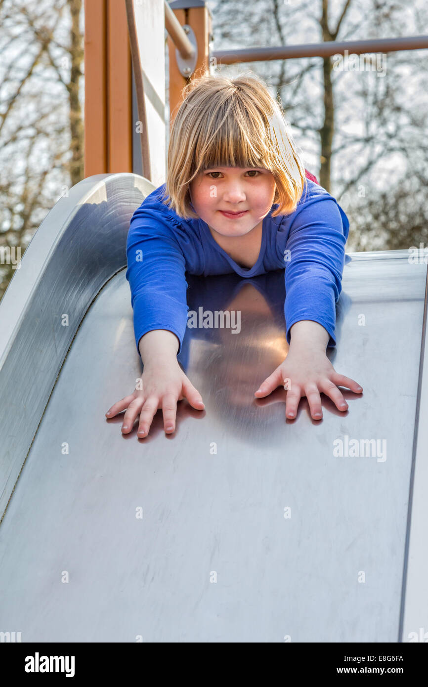 Young caucasian girl lies forward on slide Stock Photo