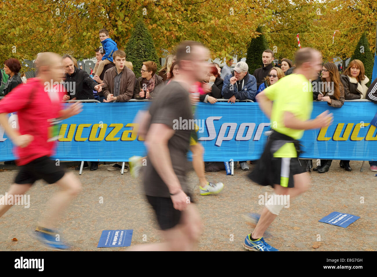 Spectators encourage marathon runners approaching the finish line at