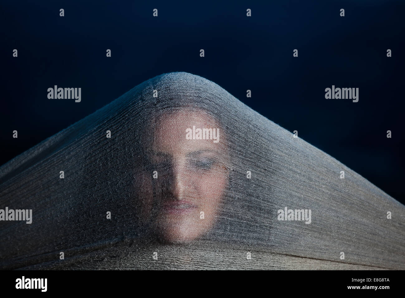 Ghost woman face hidden behind a scarf in the night with strange weird scary looking Stock Photo
