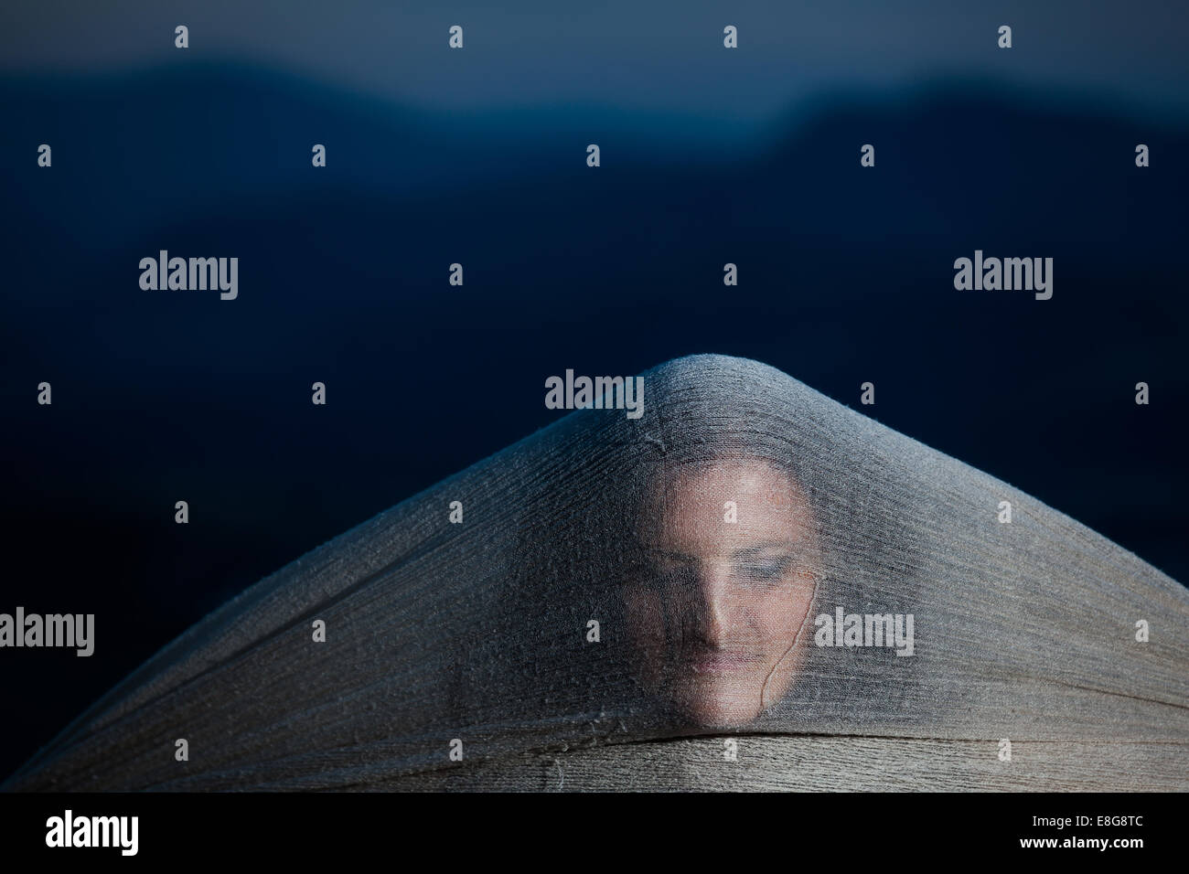 Ghost woman face hidden behind a scarf in the night with strange weird scary looking Stock Photo