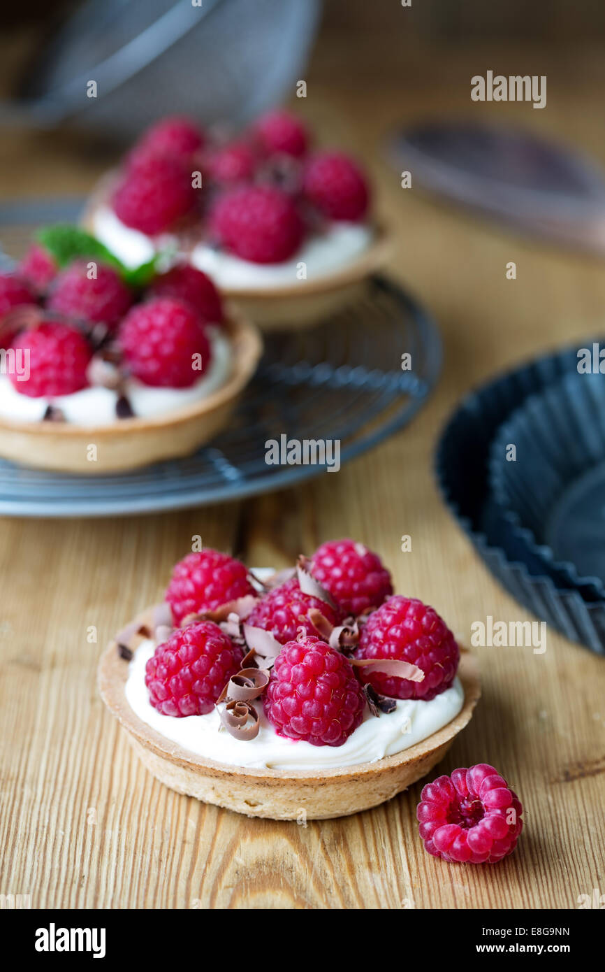 Mini tarts filled with cream and fresh raspberries Stock Photo