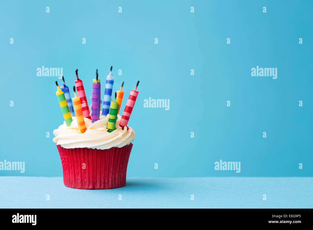 Birthday cupcake with blown out candles against a blue background Stock