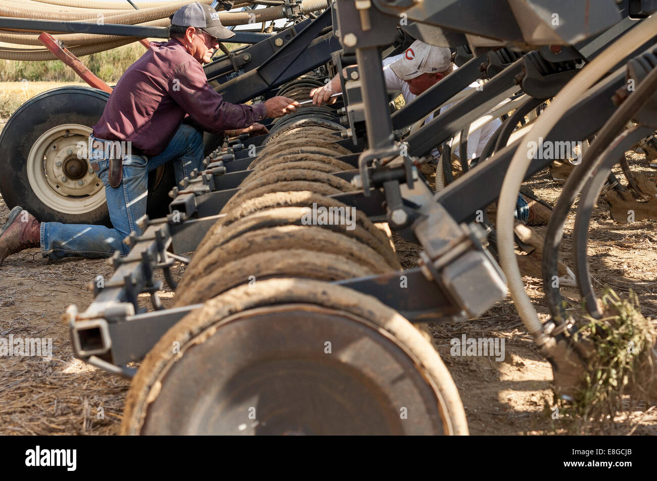 Tom Bangs, left, hands a wrench to his son Jeff, while fixing a seed