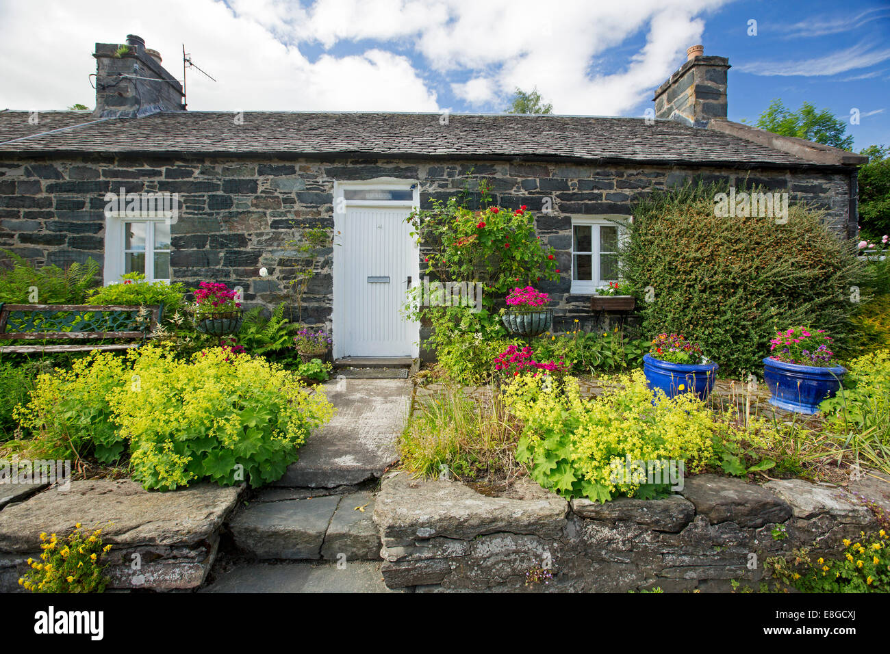 Small stone cottage with rock wall, steps, and pathway through colourful garden at village of Pitlochry, Scotland Stock Photo