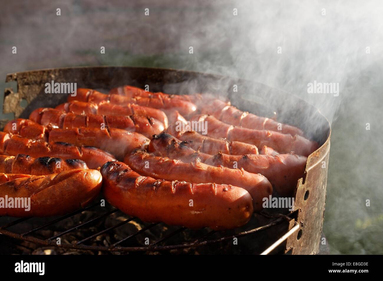 delicious polish kielbasa sausages on grill barbecue, visible smoke Stock Photo