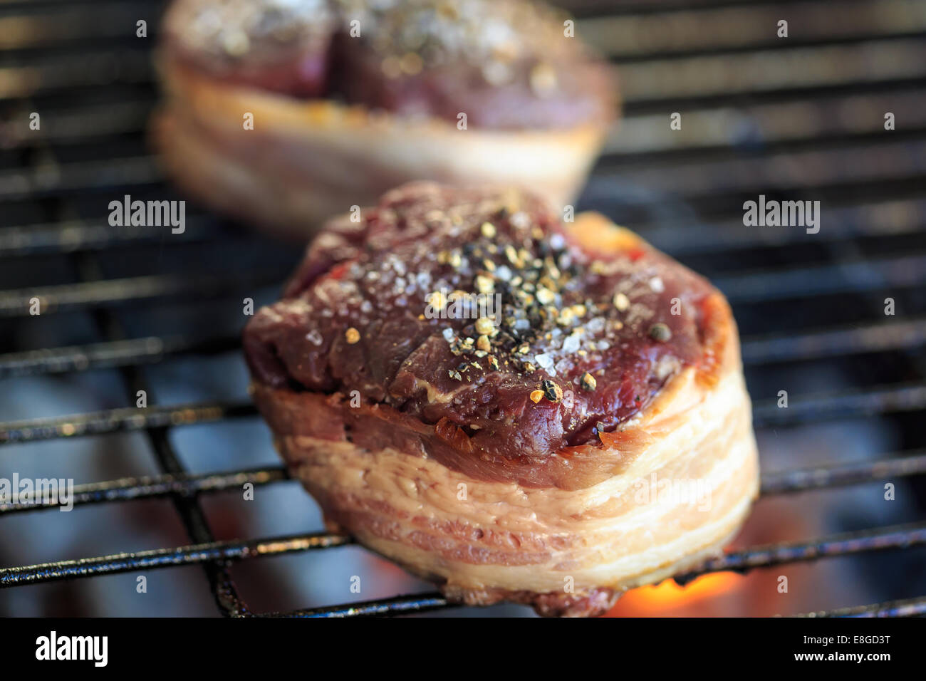 Two fillet mignon beef steaks wrapped in bacon and topped with coarse sea salt and cracked pepper corns. Stock Photo
