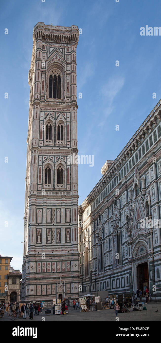 Street artists outside Giotto's Campanile beside the Duomo in Florence, Tuscany, Italy, with tourists milling around. Stock Photo