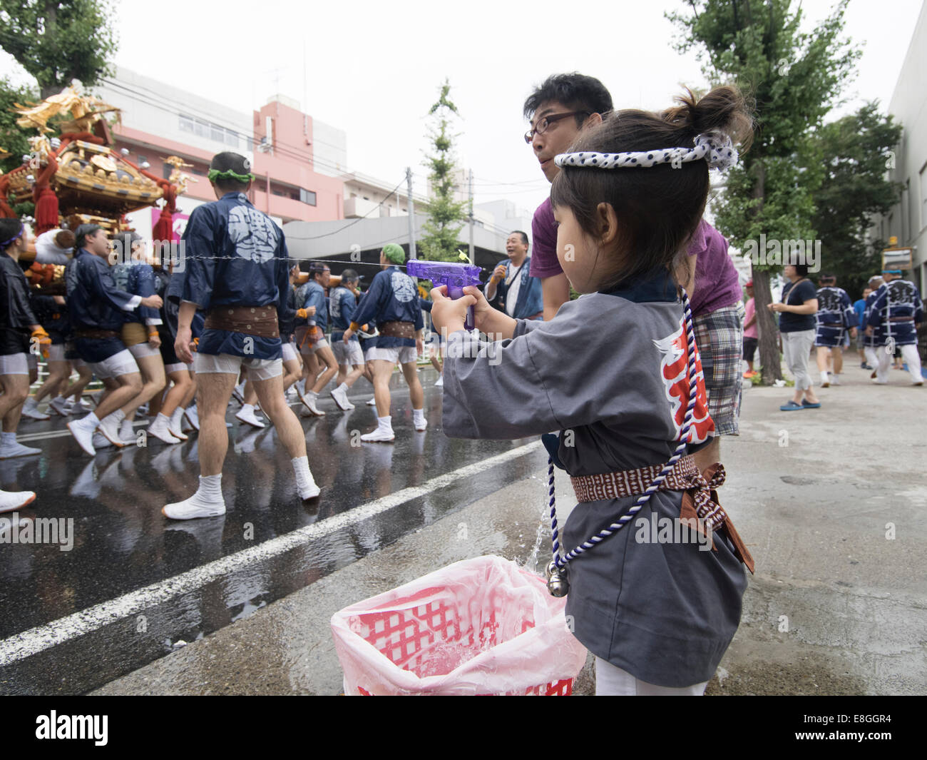 Girl with water pistol at Fukagawa Fetival aka water throwing festival held at Tomioka Hachimangu Shrine, Tokyo, Japan Stock Photo
