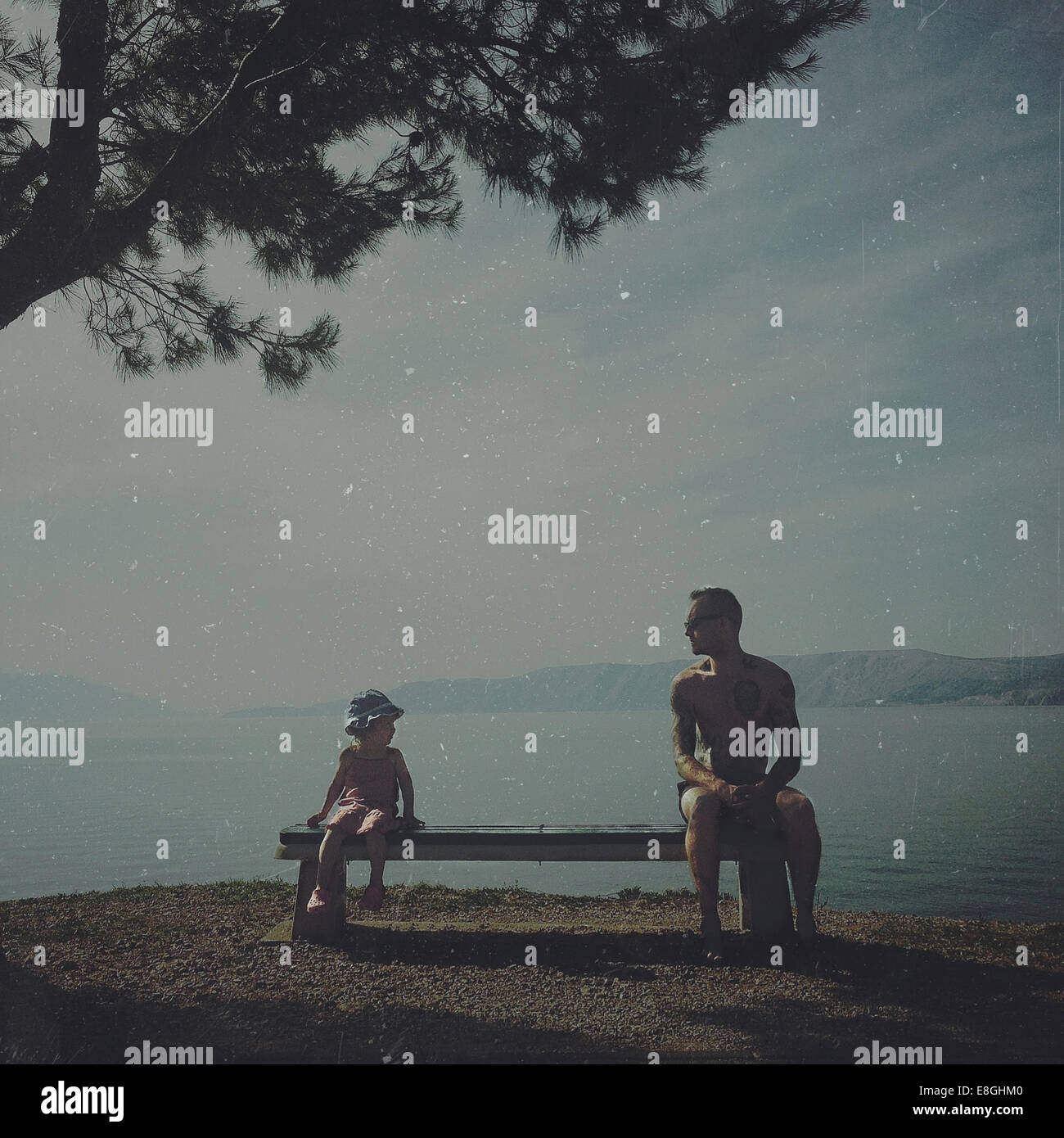 Father and daughter sitting on a bench by the sea, Croatia Stock Photo