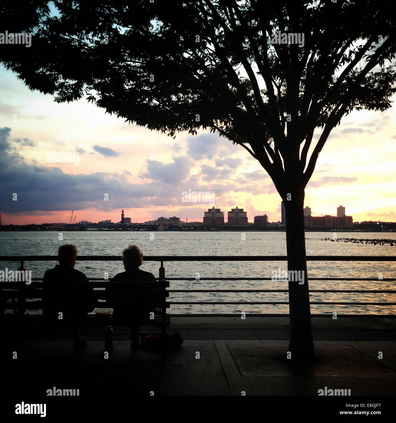 USA, New York State, New York City, Couple sitting on bench at sunset Stock Photo