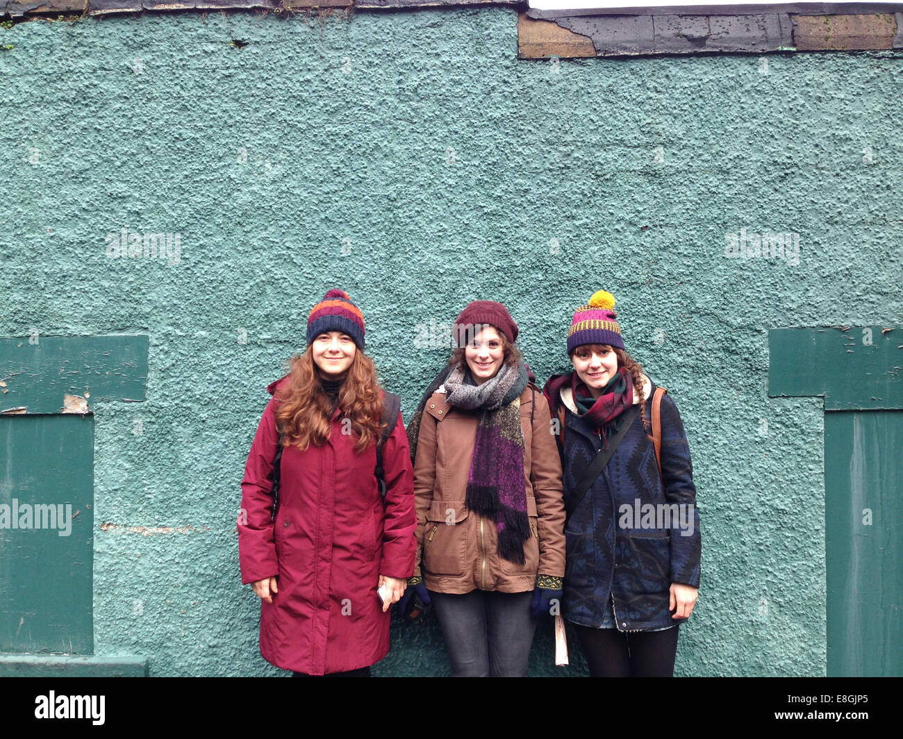 Three women standing against a wall Stock Photo