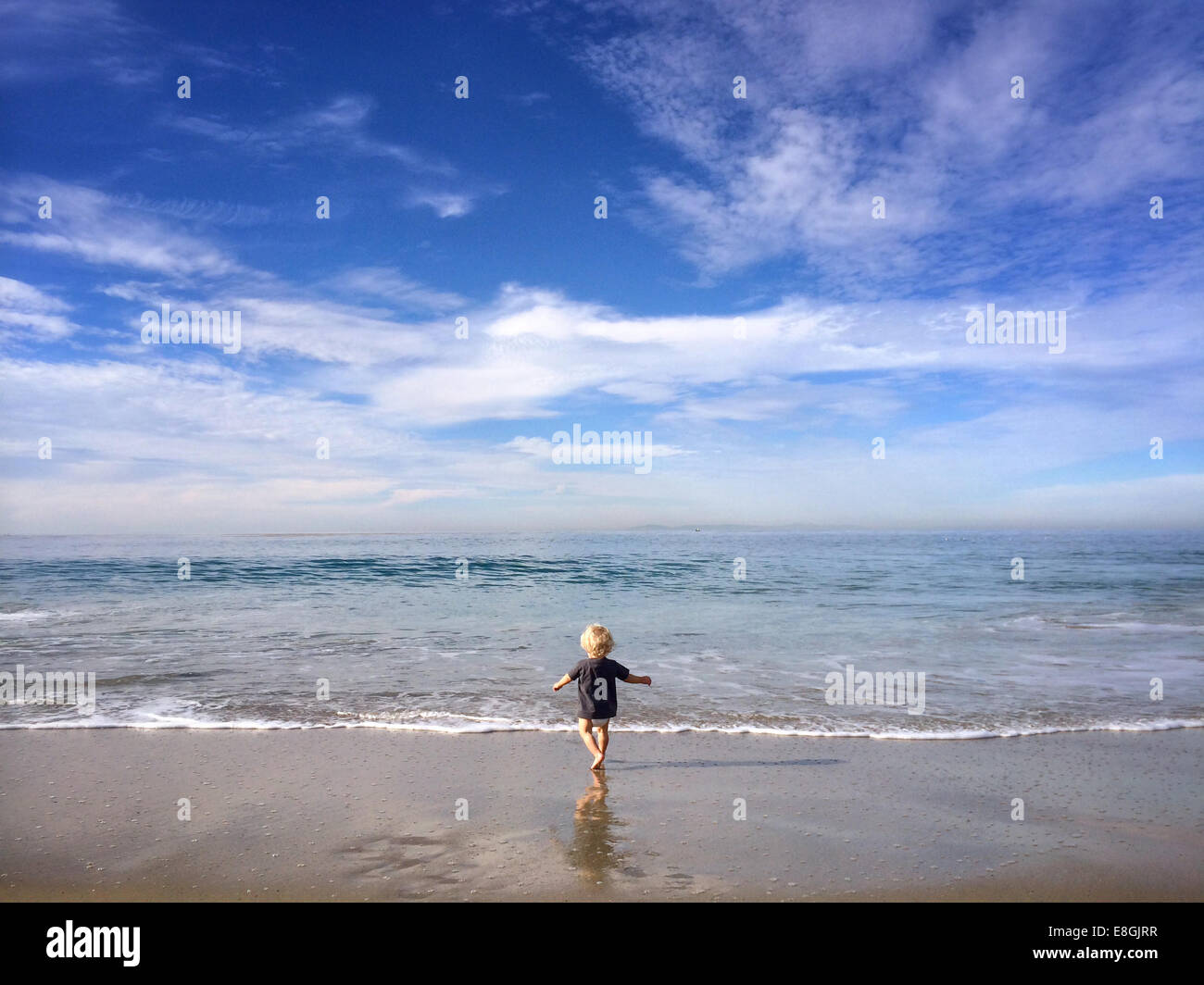 Boy running into the ocean, California, United States Stock Photo