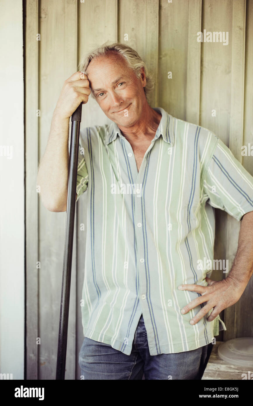 Portrait of smiling man with shovel standing against wall Stock Photo
