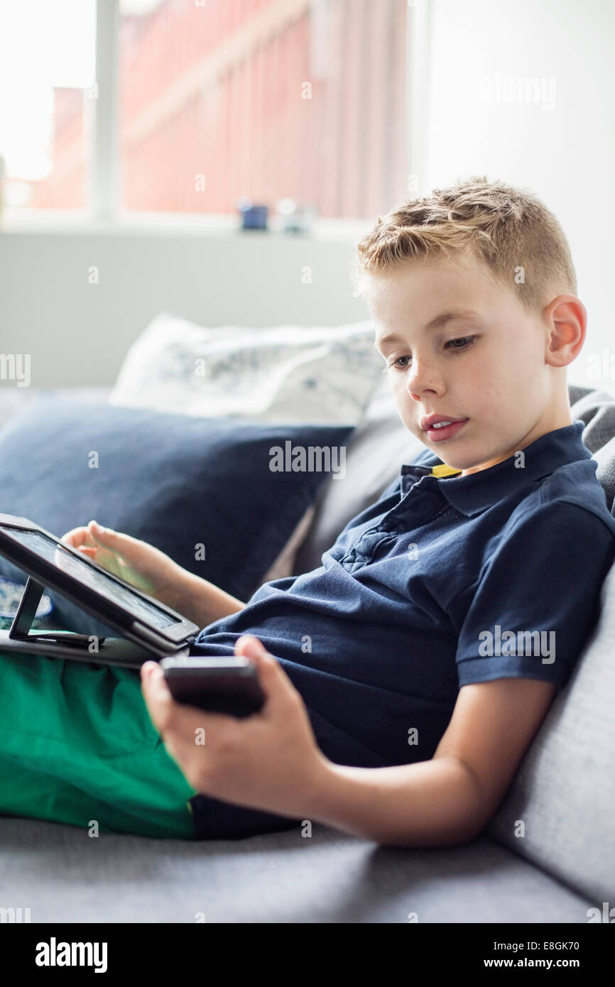 Boy using technologies on sofa at home Stock Photo - Alamy