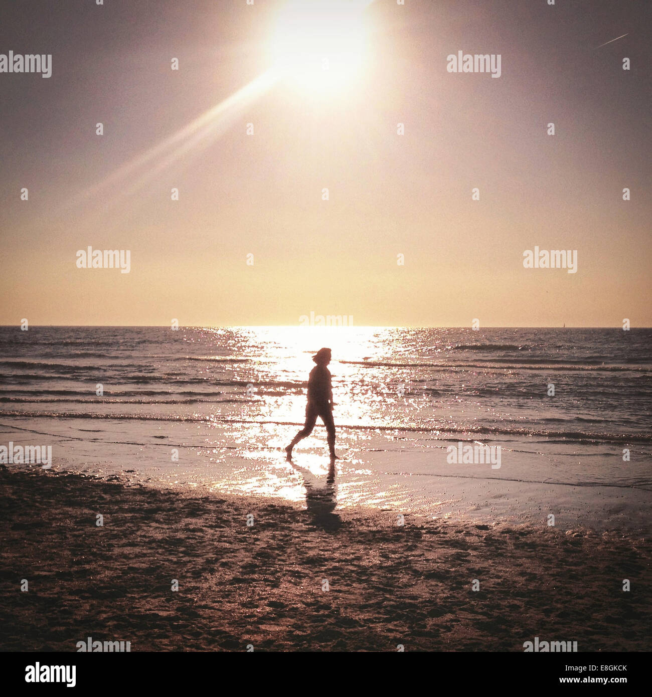 Woman walking on beach at sunset Stock Photo - Alamy