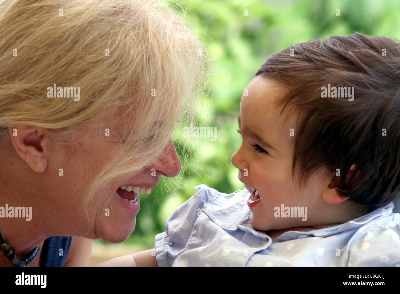 Portrait of Grandmother and granddaughter looking at each other laughing Stock Photo