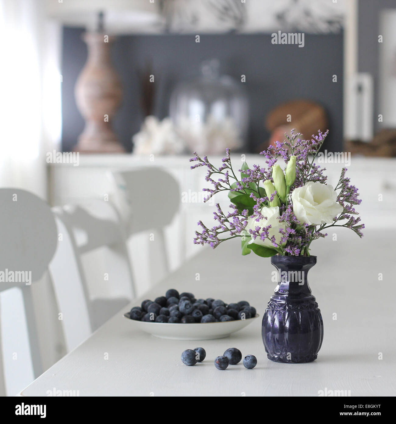 Vase with flowers and bowl with blueberries Stock Photo