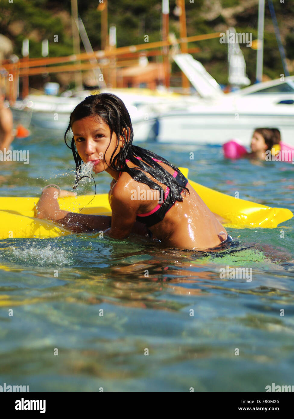 Girl on an inflatable raft in sea spitting out water Stock Photo