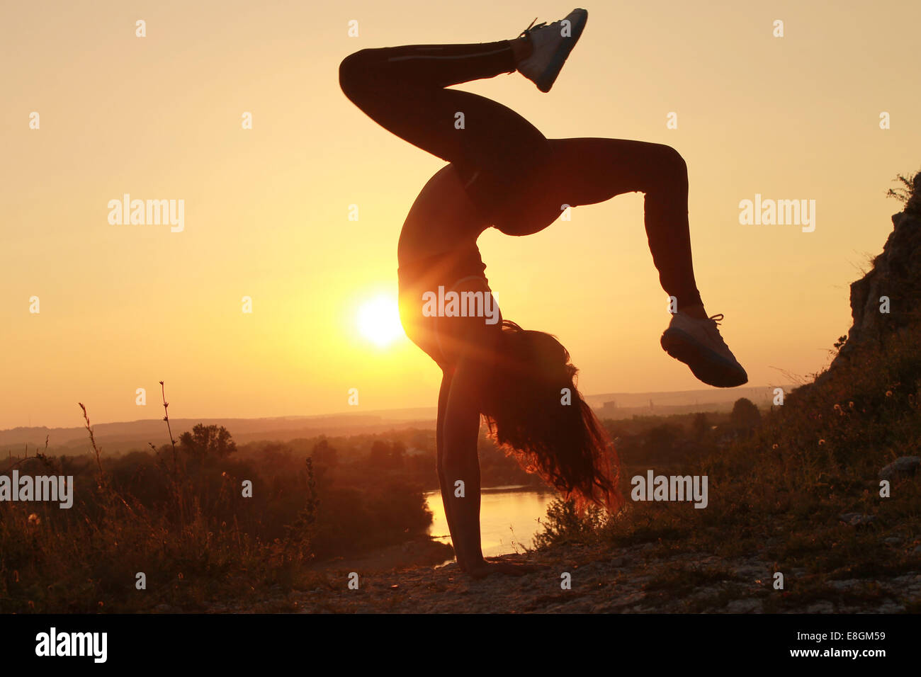 Young woman doing handstand at sunset Stock Photo