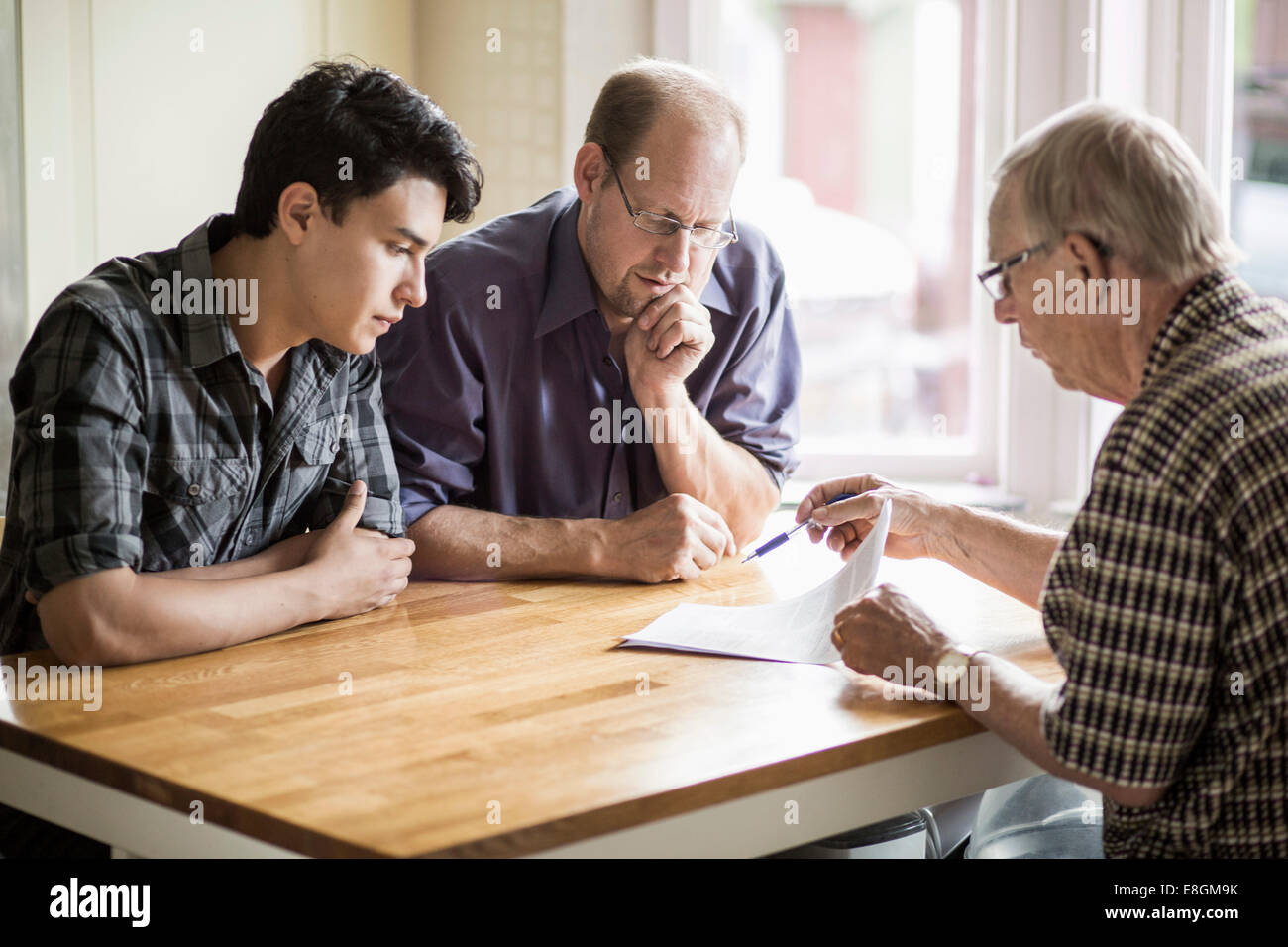  A family is gathered around a table having a serious discussion while looking at paperwork.
