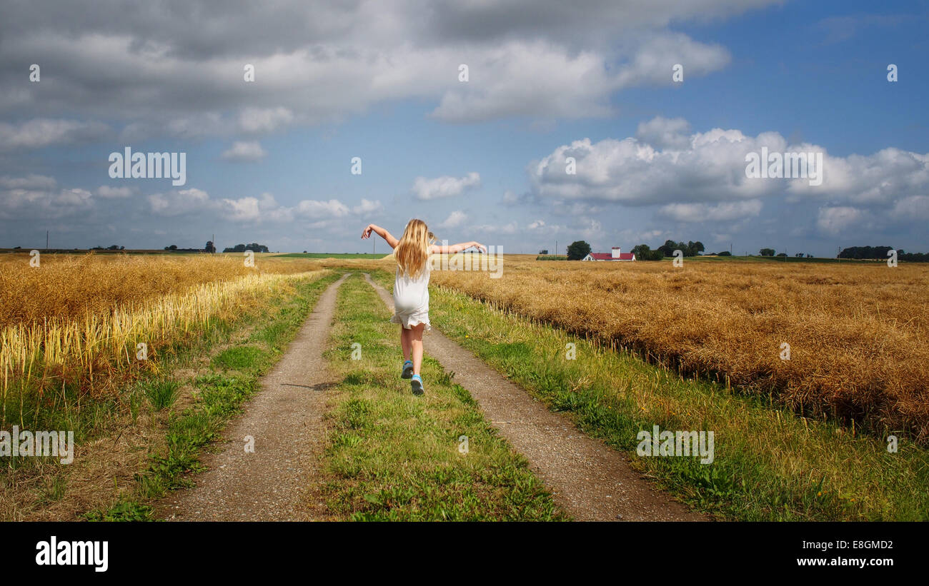 Girl skipping down a gravel road in the summer, South Sweden, Sweden Stock Photo