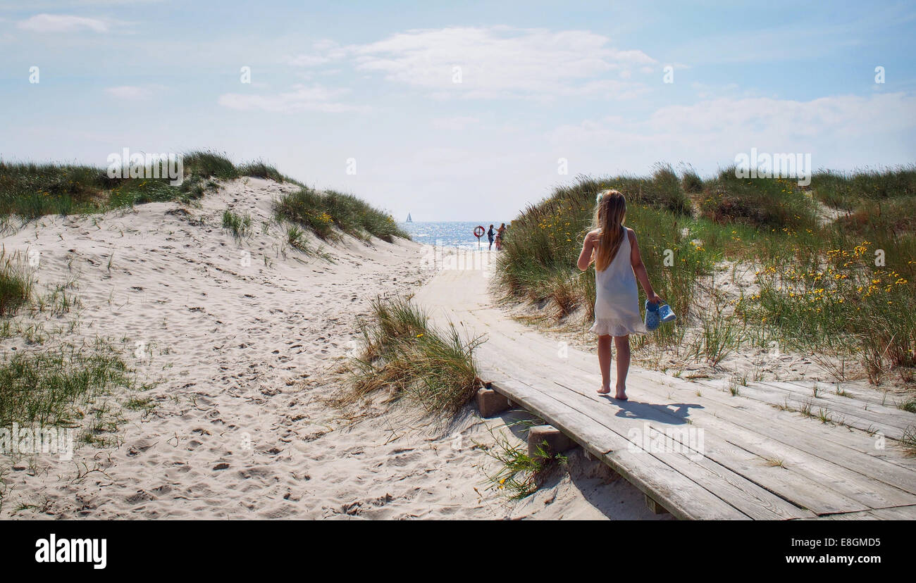Girl walking along a wooden walkway to the beach, Sweden Stock Photo
