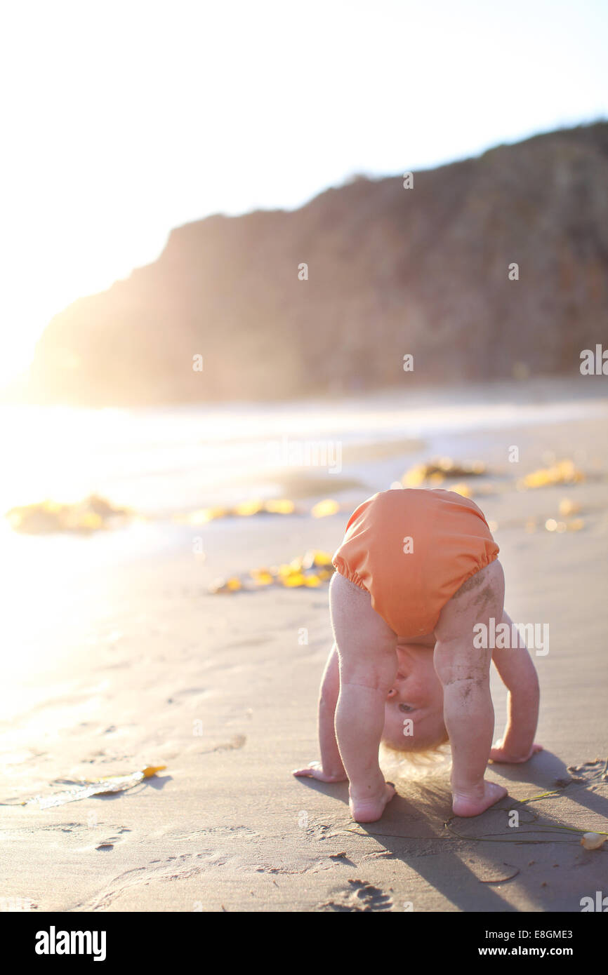 Toddler bending over on beach Stock Photo