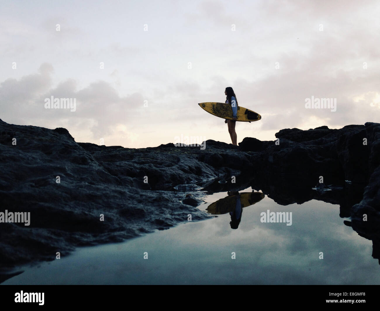 Girl standing on beach with her surfboard, Jacksonville, Florida Stock