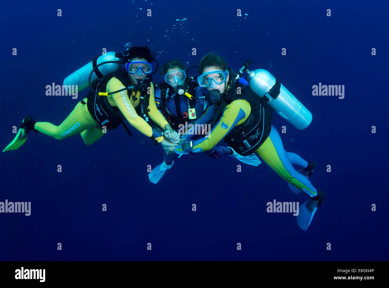 Group of scuba divers with colourful diving suits in the open water
