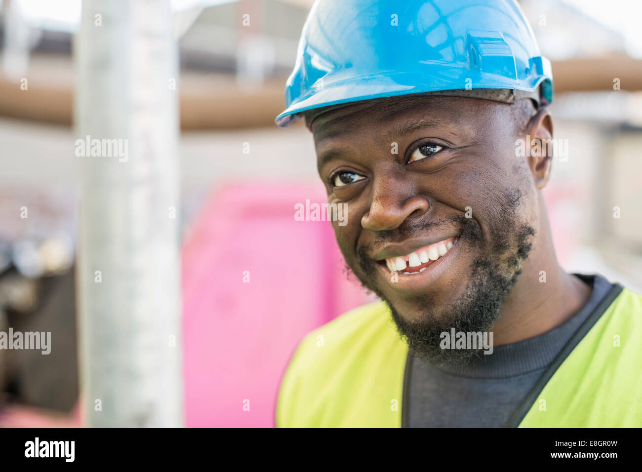 Happy construction worker looking away at site Stock Photo - Alamy