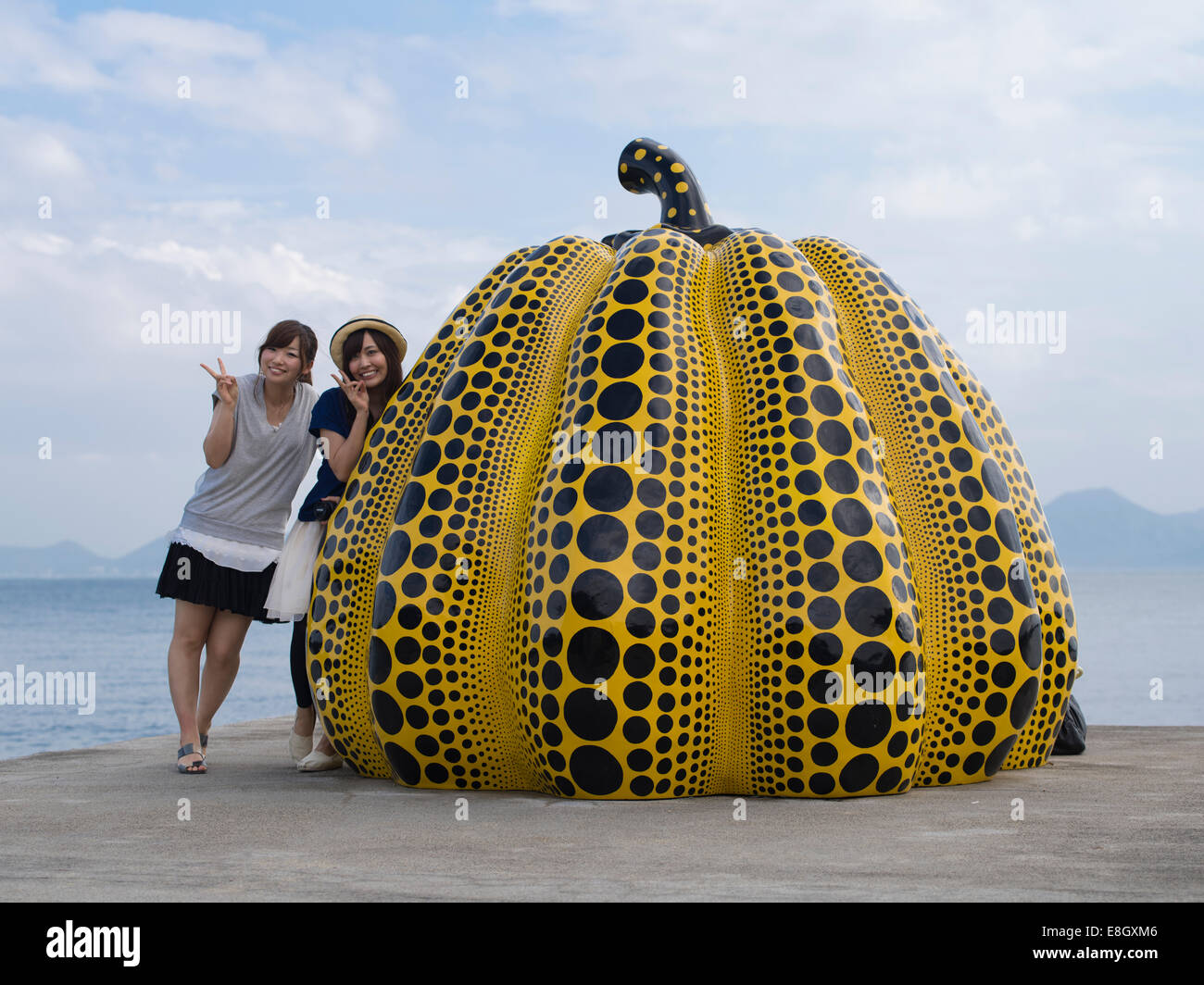 Women walk by the Pumpkin sculptures by Japanese artist Yayoi