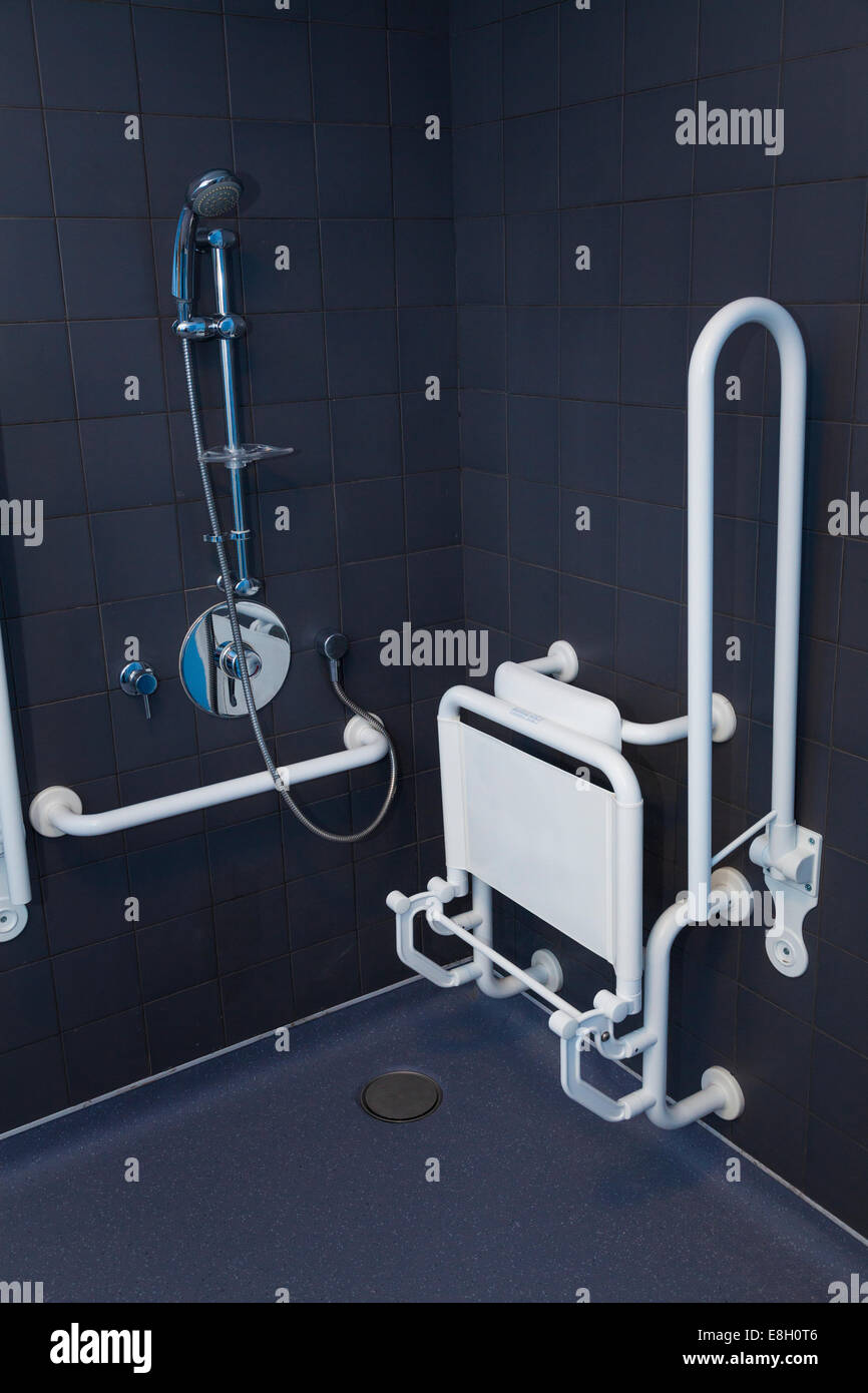 Disabled shower in wet room with hand rails and seat in up position. Stock Photo