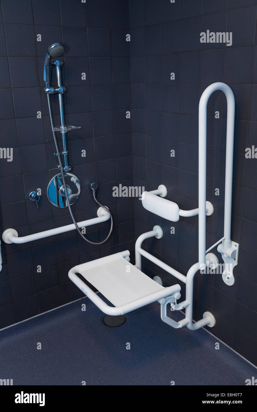 Disabled shower in wet room with hand rails and seat in down position. Stock Photo