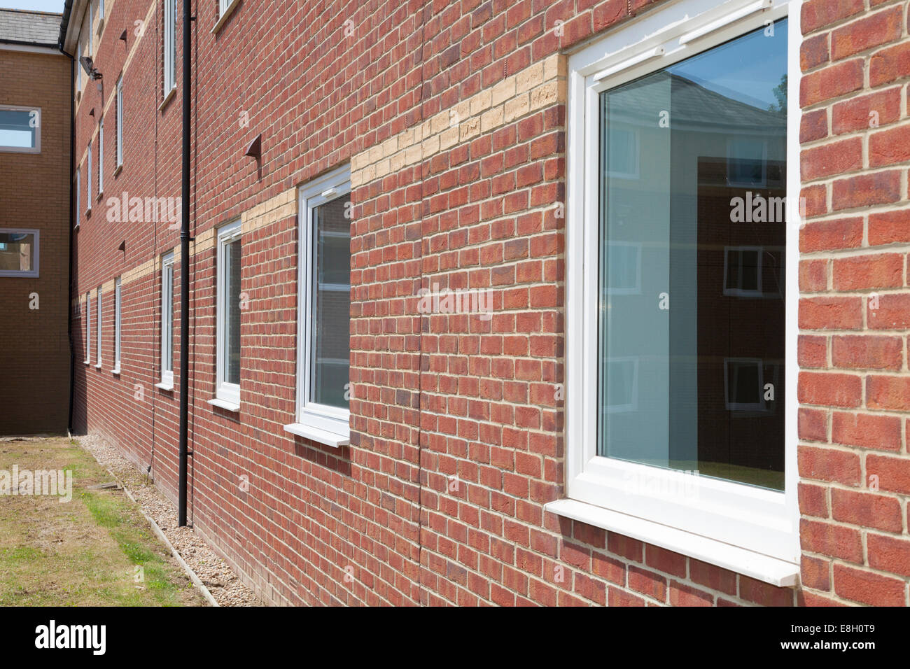 Perspective of white windows in red brick wall on commercial building. Stock Photo