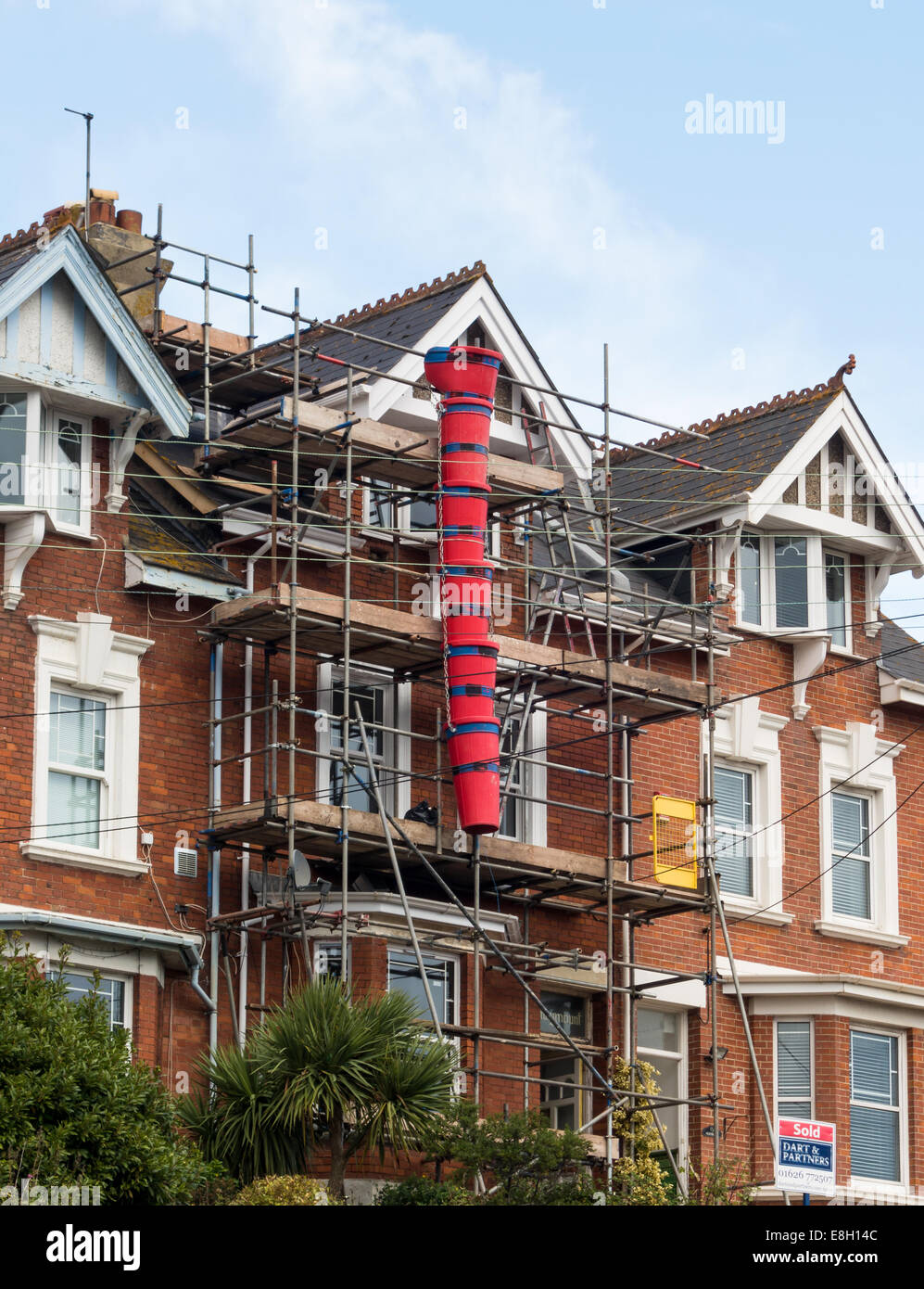 Scaffolding covering the front of a town house at Teignmouth in Devon. A red bucket chute included for debris disposal. Stock Photo